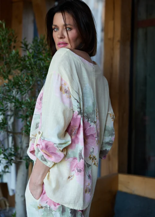 Bluzka damska w cytrynowym odcieniu z pastelowym kwiatowym printem, o luźnym kroju z rękawami 3/4 i podwijanymi mankietami, stylizowana z szerokimi spodniami w eleganckim, naturalnym zestawie.