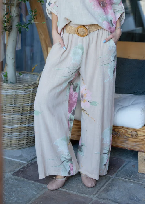 Beżowe szerokie spodnie damskie z kwiatowym printem, z wysokim stanem i paskiem w talii, o lekkim, zwiewnym fasonie, stylizowane w naturalnym, eleganckim looku.