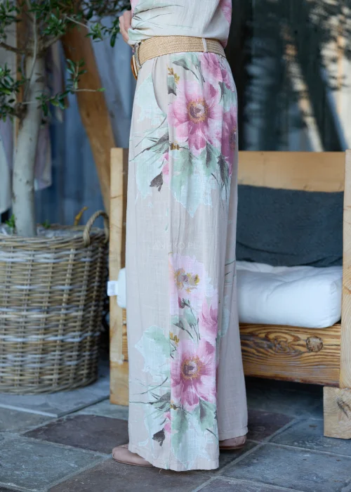 Beżowe szerokie spodnie damskie z kwiatowym printem, z wysokim stanem i paskiem w talii, o lekkim, zwiewnym fasonie, stylizowane w naturalnym, eleganckim looku.