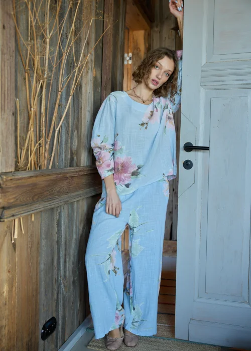 Spodnie damskie w kolorze błękitnym z kwiatowym printem, o szerokich nogawkach, stylizowane z dopasowaną bluzką i paskiem w naturalnym stylu.