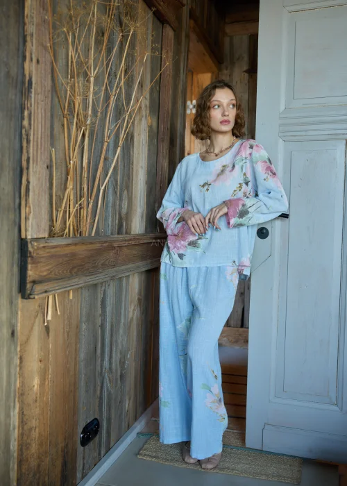 Spodnie damskie w kolorze błękitnym z kwiatowym printem, o szerokich nogawkach, stylizowane z dopasowaną bluzką i paskiem w naturalnym stylu.