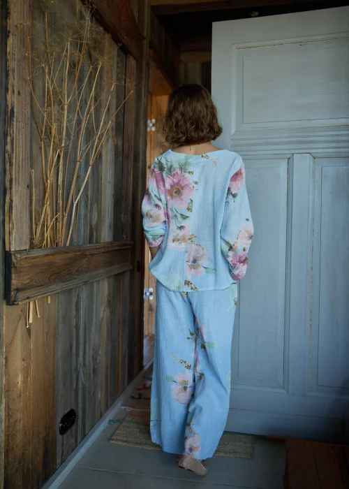 Spodnie damskie w kolorze błękitnym z kwiatowym printem, o szerokich nogawkach, stylizowane z dopasowaną bluzką i paskiem w naturalnym stylu.