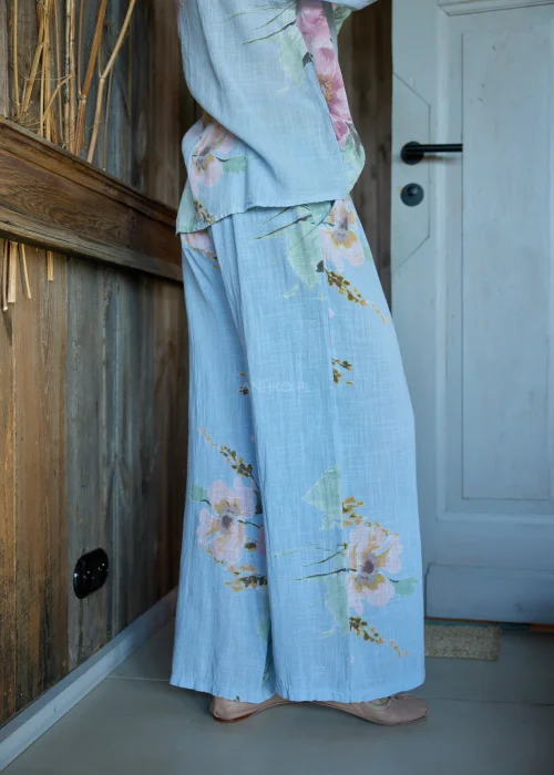 Spodnie damskie w kolorze błękitnym z kwiatowym printem, o szerokich nogawkach, stylizowane z dopasowaną bluzką i paskiem w naturalnym stylu.