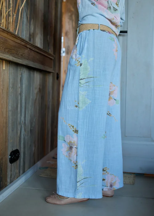 Spodnie damskie w kolorze błękitnym z kwiatowym printem, o szerokich nogawkach, stylizowane z dopasowaną bluzką i paskiem w naturalnym stylu.