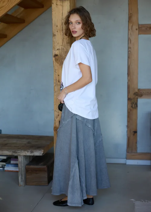 Biała bluzka damska z nadrukiem różowego auta i balonów, o luźnym kroju, stylizowana z szarymi spodniami i biżuterią.