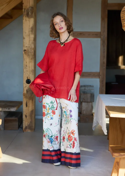 Białe spodnie damskie typu wide leg w kolorowy kwiatowy wzór z szeroką nogawką i elastycznym pasem, wykończone kontrastowym paskiem, styl casual premium.