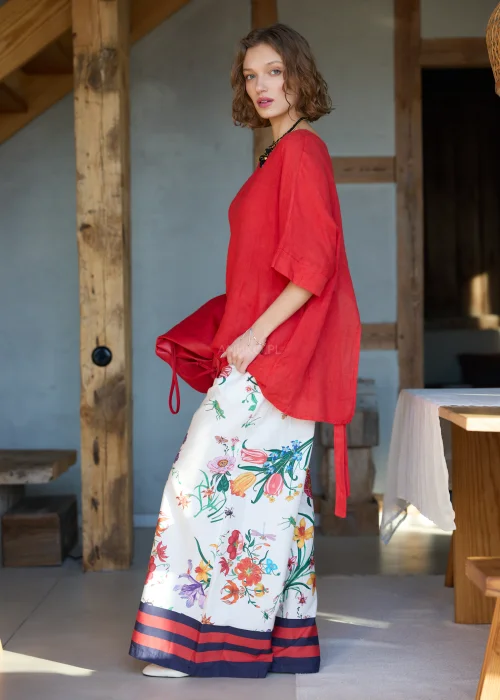 Białe spodnie damskie typu wide leg w kolorowy kwiatowy wzór z szeroką nogawką i elastycznym pasem, wykończone kontrastowym paskiem, styl casual premium.