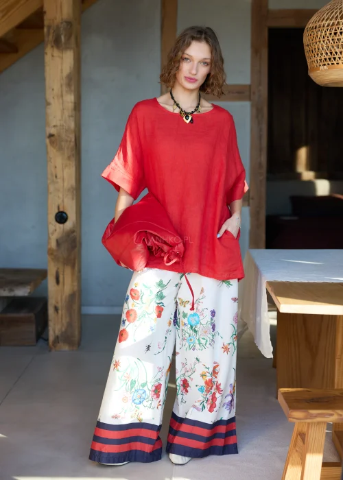 Lniana bluzka damska w intensywnym czerwonym kolorze z krótkim rękawem i wiązaniem na plecach, luźny fason, stylizacja z kwiatową spódnicą.