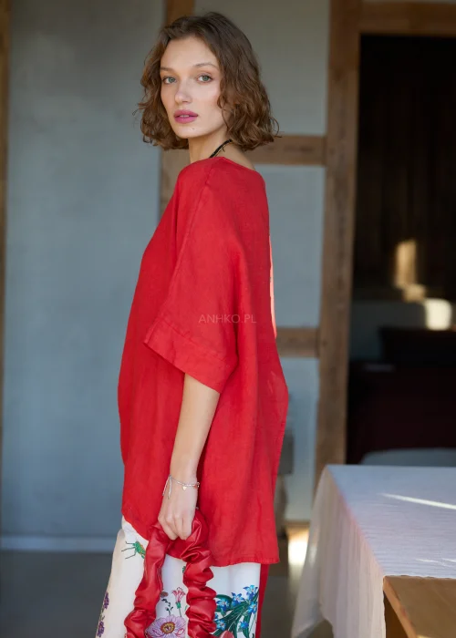 Lniana bluzka damska w intensywnym czerwonym kolorze z krótkim rękawem i wiązaniem na plecach, luźny fason, stylizacja z kwiatową spódnicą.