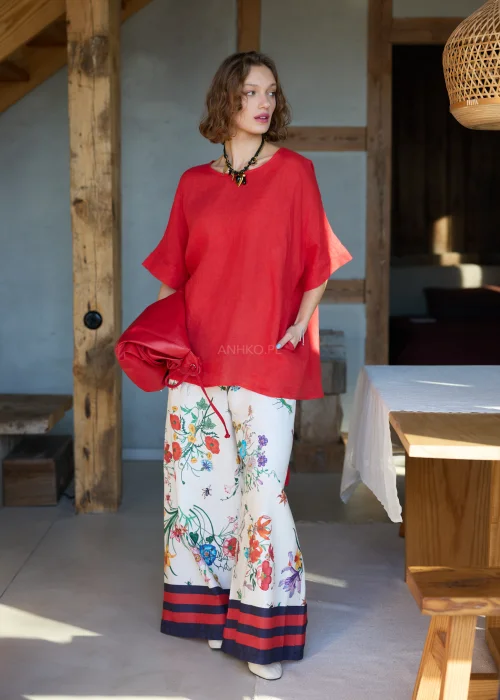 Lniana bluzka damska w intensywnym czerwonym kolorze z krótkim rękawem i wiązaniem na plecach, luźny fason, stylizacja z kwiatową spódnicą.