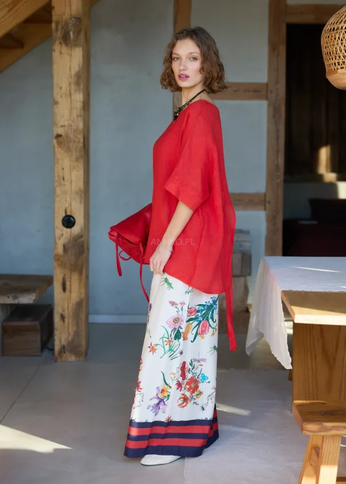 Lniana bluzka damska w intensywnym czerwonym kolorze z krótkim rękawem i wiązaniem na plecach, luźny fason, stylizacja z kwiatową spódnicą.