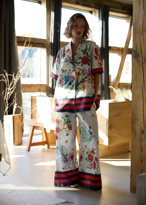 Biała koszula damska oversize w kolorowy kwiatowy wzór z krótkim rękawem i kołnierzykiem, wykończona kontrastowym paskiem.