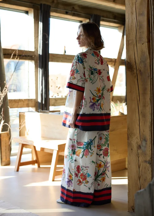 Biała koszula damska oversize w kolorowy kwiatowy wzór z krótkim rękawem i kołnierzykiem, wykończona kontrastowym paskiem.