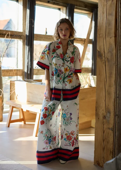 Biała koszula damska oversize w kolorowy kwiatowy wzór z krótkim rękawem i kołnierzykiem, wykończona kontrastowym paskiem.