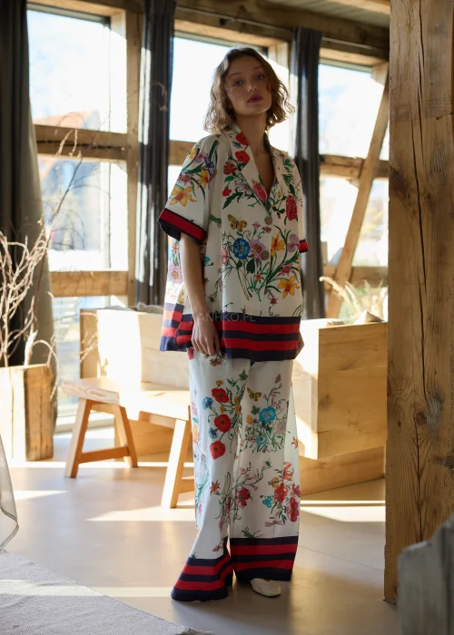 Biała koszula damska oversize w kolorowy kwiatowy wzór z krótkim rękawem i kołnierzykiem, wykończona kontrastowym paskiem.