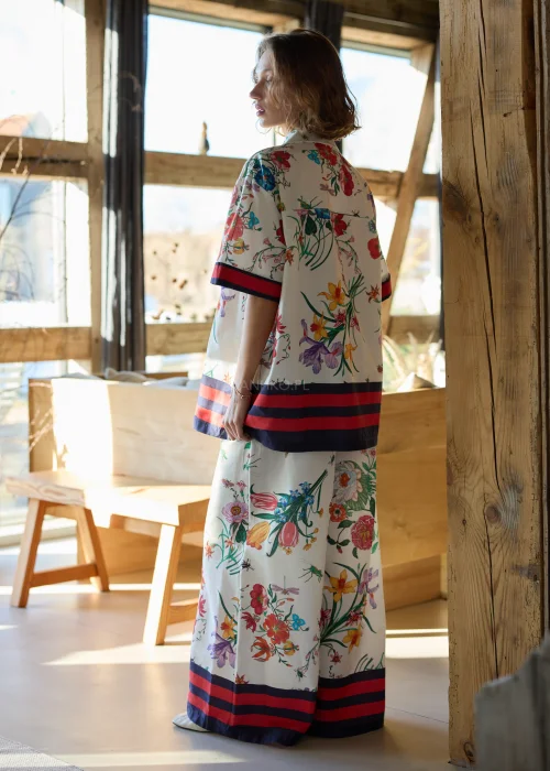 Biała koszula damska oversize w kolorowy kwiatowy wzór z krótkim rękawem i kołnierzykiem, wykończona kontrastowym paskiem.