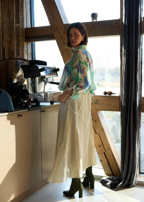 Beżowa spódnica midi z naturalnej tkaniny z surowymi przeszyciami i elastyczną talią, styl casual z botkami na obcasie.