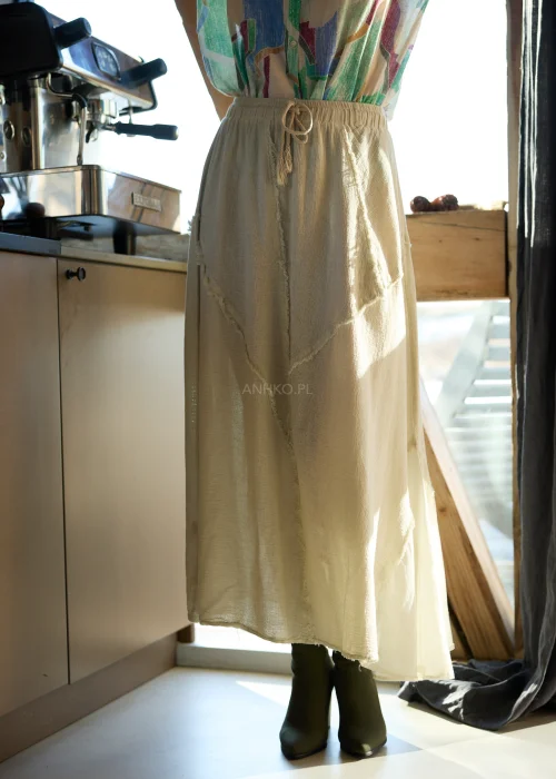 Beżowa spódnica midi z naturalnej tkaniny z surowymi przeszyciami i elastyczną talią, styl casual z botkami na obcasie.