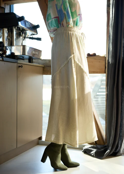 Beżowa spódnica midi z naturalnej tkaniny z surowymi przeszyciami i elastyczną talią, styl casual z botkami na obcasie.