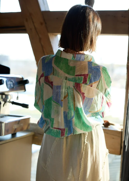 Koszula damska w geometryczny wzór w odcieniach zieleni, beżu i błękitu, o luźnym kroju, z kołnierzykiem i podwijanymi rękawami.