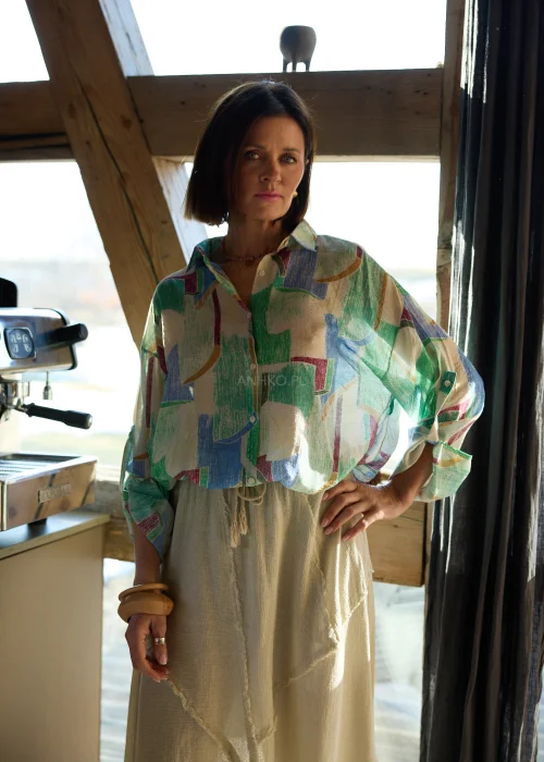 Koszula damska w geometryczny wzór w odcieniach zieleni, beżu i błękitu, o luźnym kroju, z kołnierzykiem i podwijanymi rękawami.