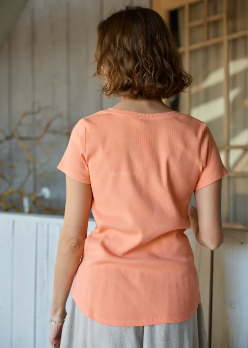 Bluzka damska prążkowana w kolorze brzoskwiniowym, z krótkim rękawem i dekoltem na guziki, o dopasowanym fasonie.