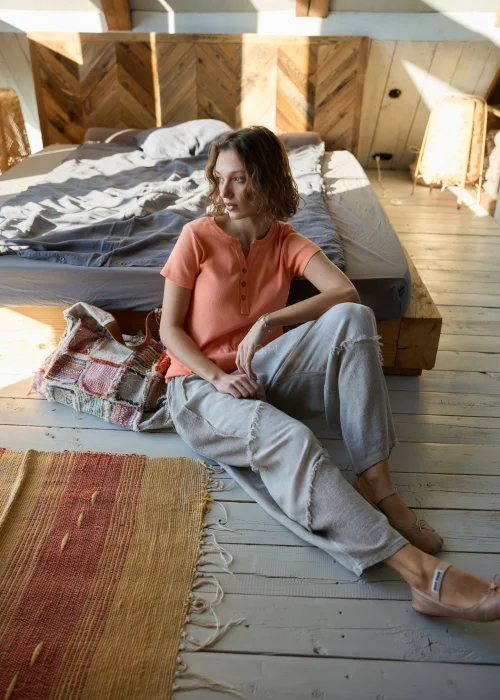 Bluzka damska prążkowana w kolorze brzoskwiniowym, z krótkim rękawem i dekoltem na guziki, o dopasowanym fasonie.