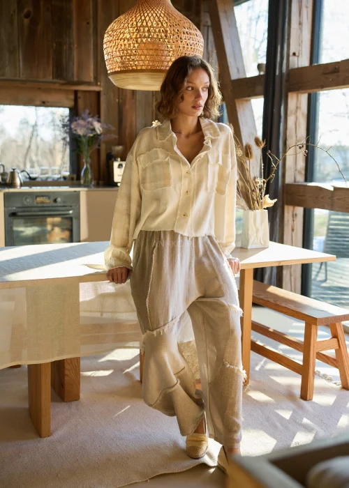 Lniana koszula damska w kolorze kremowym, o luźnym kroju, zapinana na guziki, z naszywanymi kieszeniami i surowym wykończeniem.