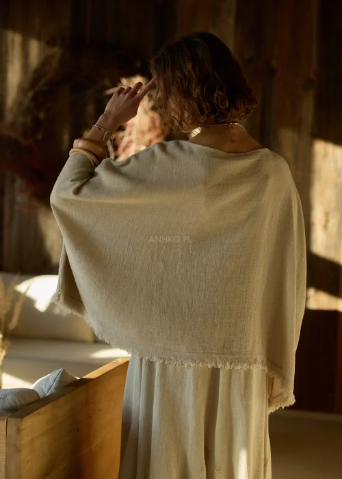 Beżowa bluzka damska oversize z dodatkiem lnu, o luźnym kroju i szerokich rękawach, stylizowana z naturalnymi dodatkami w ciepłym wnętrzu.