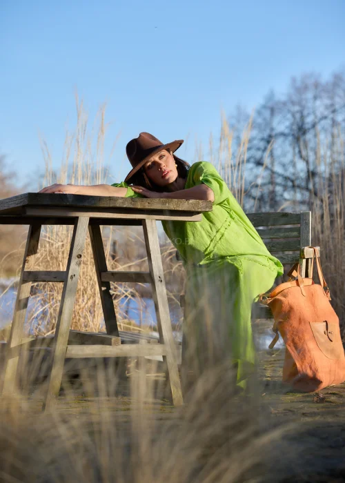 Zielona spódnica midi o luźnym kroju z surowymi przeszyciami i elastycznym pasem, stylizowana z kwiatową koszulą i botkami na obcasie w nowoczesnym looku.