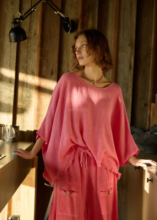 Malinowa bluzka damska oversize z dodatkiem lnu, o luźnym kroju i szerokich rękawach, stylizowana z lekkimi spodniami w naturalnym wnętrzu.