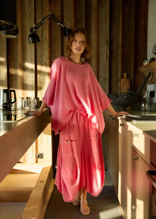 Malinowa bluzka damska oversize z dodatkiem lnu, o luźnym kroju i szerokich rękawach, stylizowana z lekkimi spodniami w naturalnym wnętrzu.