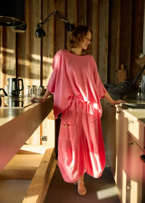 Malinowa bluzka damska oversize z dodatkiem lnu, o luźnym kroju i szerokich rękawach, stylizowana z lekkimi spodniami w naturalnym wnętrzu.