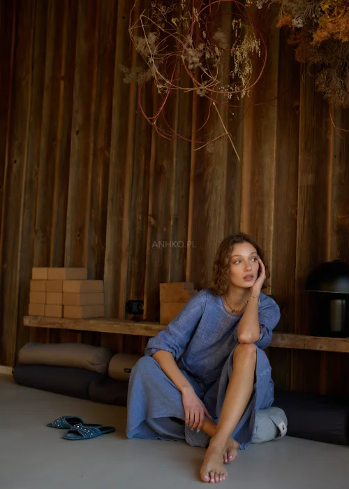 Niebieska bluzka damska o luźnym kroju z długim rękawem, z ozdobnym wiązaniem i surowym wykończeniem detali, w stylu casualowym.