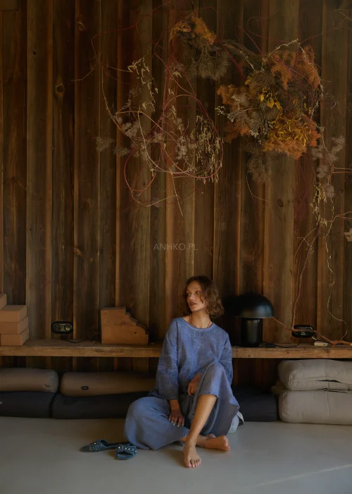 Niebieska bluzka damska o luźnym kroju z długim rękawem, z ozdobnym wiązaniem i surowym wykończeniem detali, w stylu casualowym.