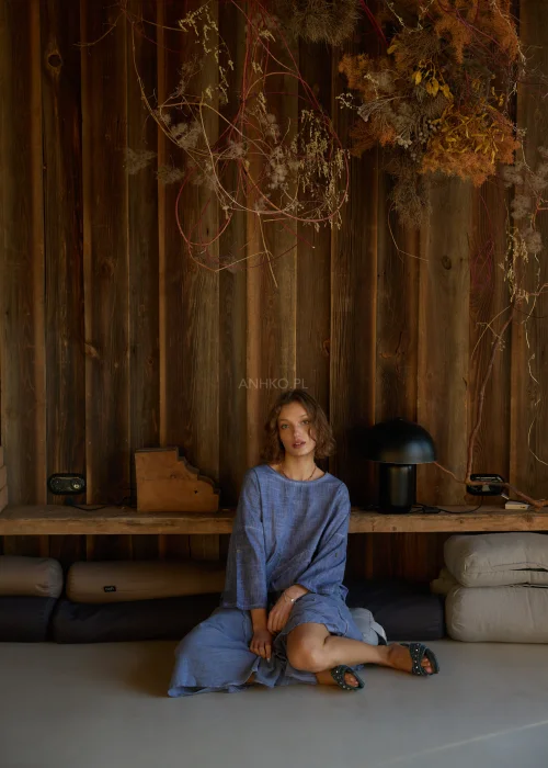 Niebieska bluzka damska o luźnym kroju z długim rękawem, z ozdobnym wiązaniem i surowym wykończeniem detali, w stylu casualowym.