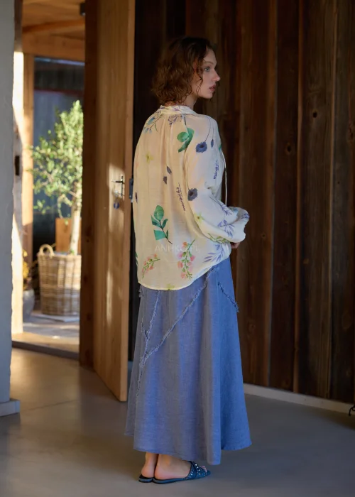 Bluzka damska w kolorze ecru z delikatnym, wielokolorowym printem roślinnym, o luźnym kroju, z dekoltem V i ozdobnymi guzikami.