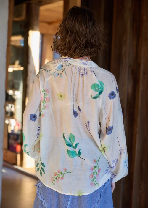 Bluzka damska w kolorze ecru z delikatnym, wielokolorowym printem roślinnym, o luźnym kroju, z dekoltem V i ozdobnymi guzikami.