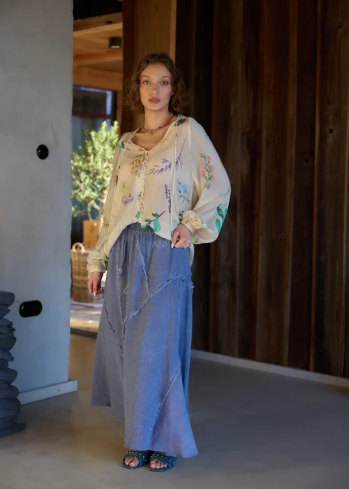 Bluzka damska w kolorze ecru z delikatnym, wielokolorowym printem roślinnym, o luźnym kroju, z dekoltem V i ozdobnymi guzikami.