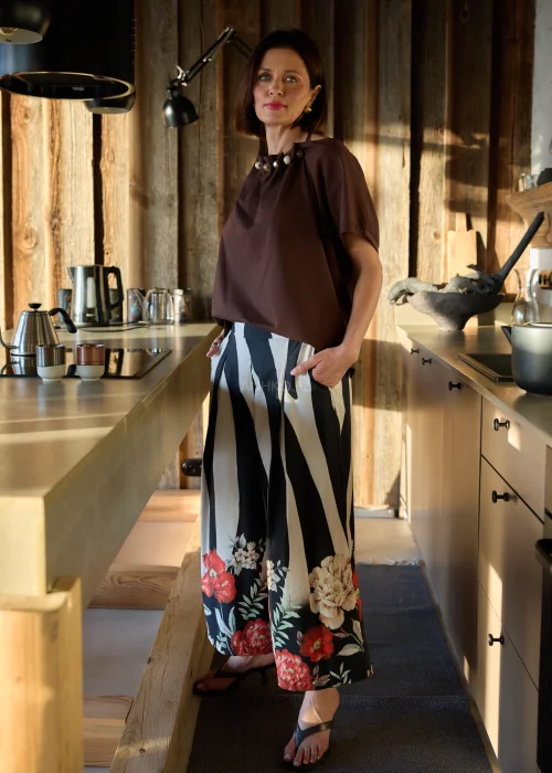 Spodnie damskie w czarno-białe pasy z kwiatowym nadrukiem, szerokie nogawki i wysoki stan, elegancki, lekko oversize fason.