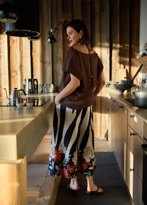 Spodnie damskie w czarno-białe pasy z kwiatowym nadrukiem, szerokie nogawki i wysoki stan, elegancki, lekko oversize fason.