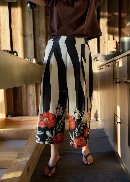 Spodnie damskie w czarno-białe pasy z kwiatowym nadrukiem, szerokie nogawki i wysoki stan, elegancki, lekko oversize fason.