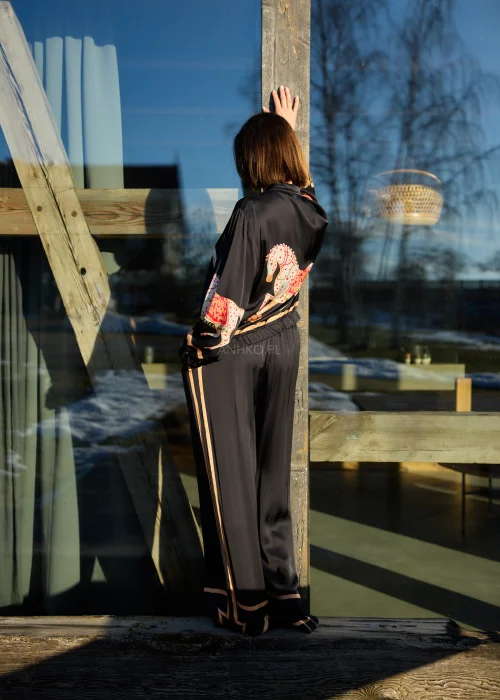 Czarne spodnie damskie z szeroką nogawką i elastyczną talią, ozdobione kontrastowymi brzoskwiniowymi lampasami.