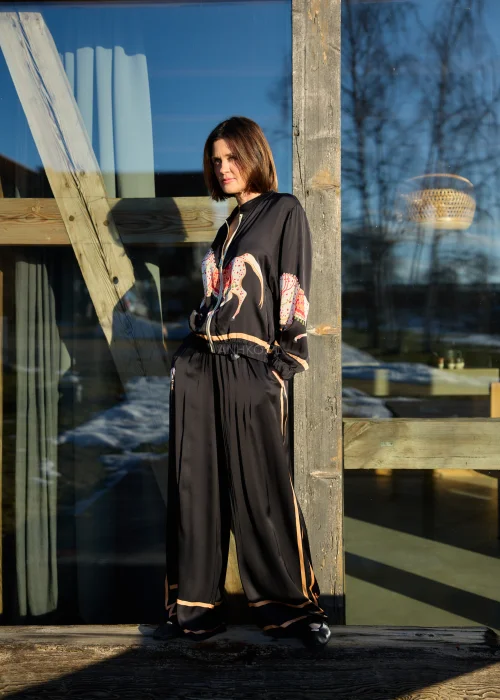 Czarne spodnie damskie z szeroką nogawką i elastyczną talią, ozdobione kontrastowymi brzoskwiniowymi lampasami.