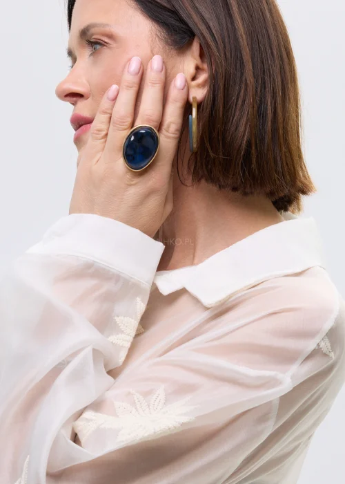 Duży pierścionek damski z owalnym, chabrowym kamieniem w złotej oprawie, o wyrazistym, eleganckim charakterze.