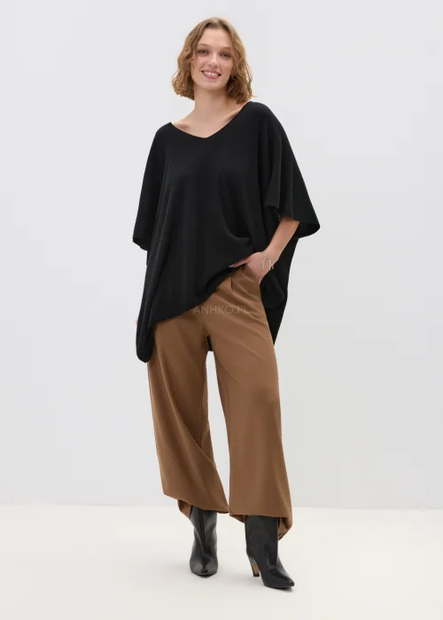 Camelowe spodnie damskie z szeroką nogawką o eleganckim kroju, gładki materiał, stylizowane z dopasowanym topem w minimalistycznym looku.