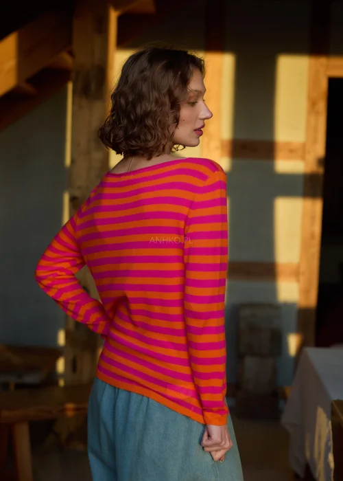 Sweter damski w różowo-pomarańczowe paski z długim rękawem, lekki fason stylizowany z luźnymi spodniami w casualowym looku.
