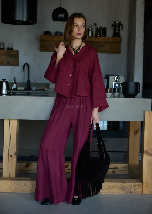 Bordowa lniana koszula oversize z długim rękawem i guzikami, o luźnym fasonie, zestawiona z bordowymi spodniami, stylizacja w naturalnym, minimalistycznym klimacie.