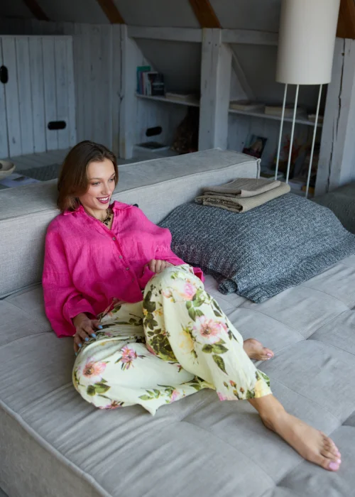 Lniana koszula oversize w odcieniu magenta z długim rękawem i guzikami, o luźnym fasonie, zestawiona z jasnymi spodniami, stylizacja w naturalnym, minimalistycznym klimacie.