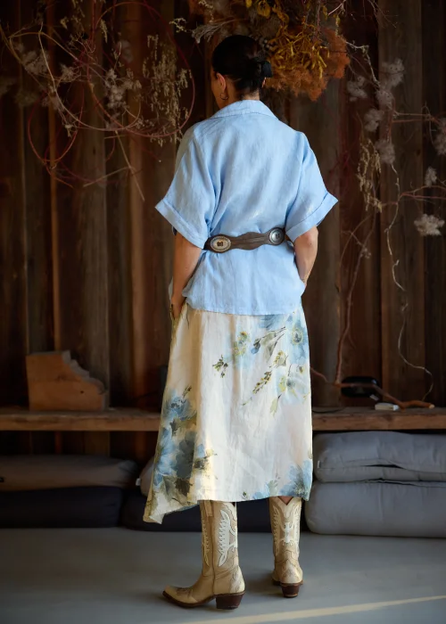 Lniana marynarka damska w kolorze baby blue o luźnym kroju, z krótkim rękawem i klasycznym kołnierzem, stylizacja warstwowa w naturalnym, eleganckim klimacie.